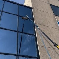 Pulizia dei vetri di un edificio con asta telescopica